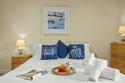 a white bed with a tray of food on it at House 31 in Looe