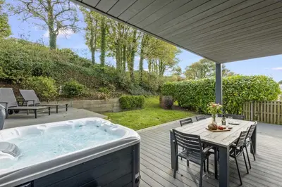 a hot tub on a deck with a table and chairs at House 31 in Looe
