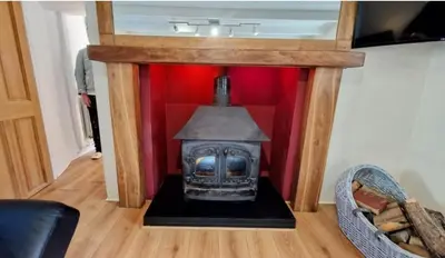 a fireplace in a room with a red wall at North Cornwall 2-Bed Detached Period Cottage With Parking in Camelford