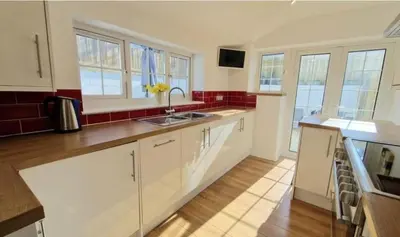 a kitchen with white cabinets and a sink at North Cornwall 2-Bed Detached Period Cottage With Parking in Camelford