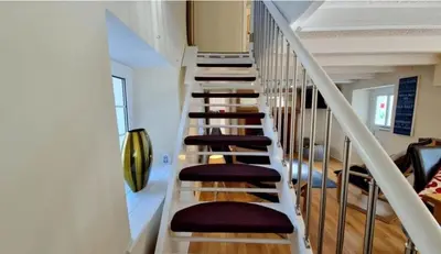 a staircase in a house with white rails and brown stools at North Cornwall 2-Bed Detached Period Cottage With Parking in Camelford