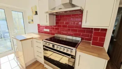 a kitchen with a stove and a red brick wall at North Cornwall 2-Bed Detached Period Cottage With Parking in Camelford