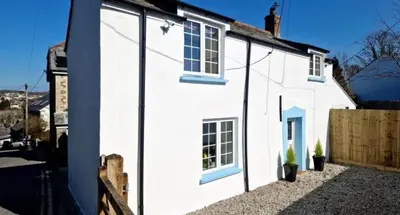 a white house with windows on the side of it at North Cornwall 2-Bed Detached Period Cottage With Parking in Camelford
