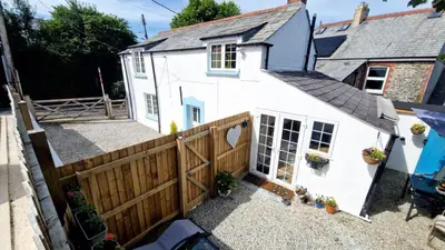 a white house with a wooden gate and a fence at North Cornwall 2-Bed Detached Period Cottage With Parking in Camelford