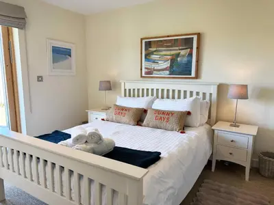 a white bed with a stuffed animal on it in a bedroom at House 32 in Looe