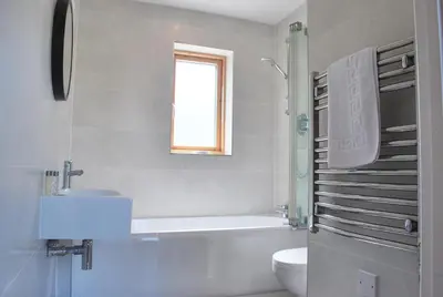 a bathroom with a tub and a toilet and a sink at House 32 in Looe