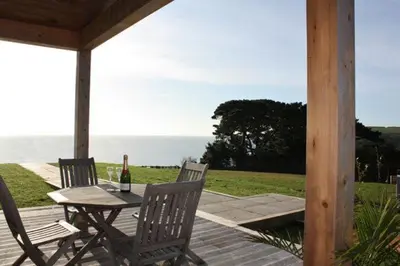 a wooden deck with a table with a bottle of wine at House 37 in Looe