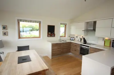 a kitchen with white cabinets and a wooden table at House 37 in Looe
