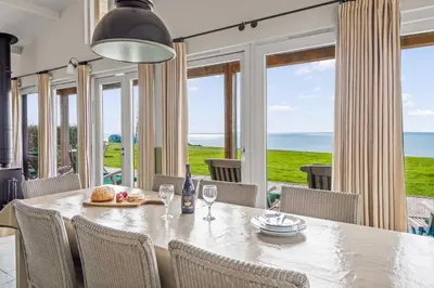 a dining room with a table and chairs and windows at House 39 in Looe