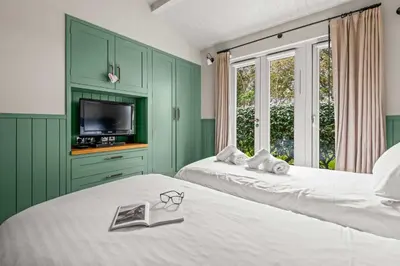 a green bedroom with two beds and a tv at House 39 in Looe
