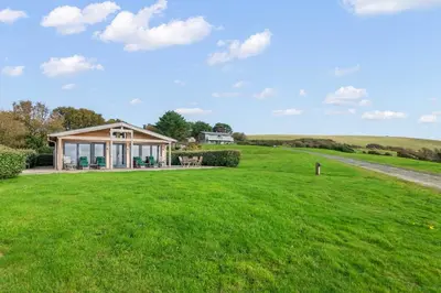 a house in a field with a green lawn at House 39 in Looe