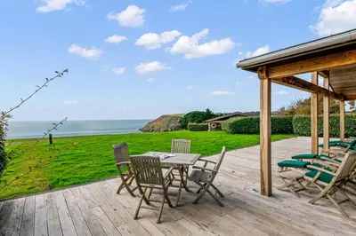 a patio with a table and chairs and the ocean at House 39 in Looe