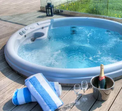 a hot tub with a bottle of champagne and wine glasses at House 38 in Looe