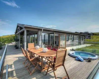 a wooden deck with a table and chairs and a house at House 38 in Looe