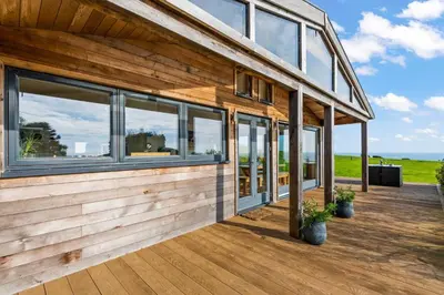 a house with large windows on a wooden deck at House 40 in Looe