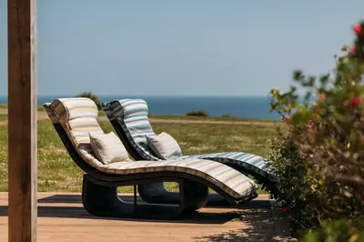 a wooden bench with pillows sitting on a patio at House 40 in Looe