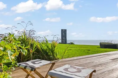 a table and two chairs sitting on a deck with the ocean at House 40 in Looe