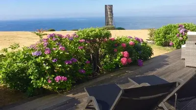 a wooden deck with flowers and a lighthouse in the background at House 41 in Looe