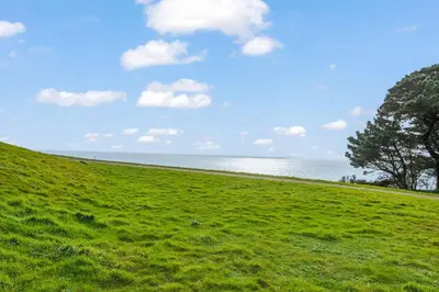 a field of green grass with the ocean in the background at House 36 in Looe
