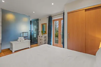 a bedroom with a large white bed and a window at House 36 in Looe