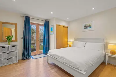 a bedroom with a white bed and a window at House 36 in Looe