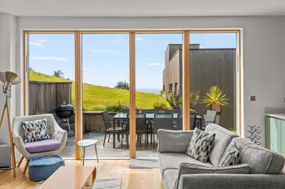 a living room with sliding glass doors and a dining room at House 45 in Looe