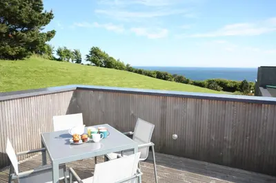 a table and chairs on a deck with the ocean at House 45 in Looe