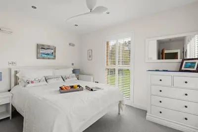 a white bedroom with a bed with a tray of fruit on it at House 5 in Looe