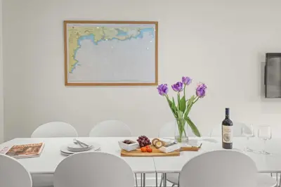 a white dining room table with a vase of purple flowers at House 8 in Looe