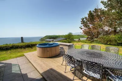 a patio with a table and chairs and a hot tub at House 42 in Looe