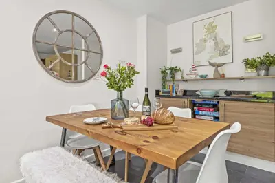 a dining room table with flowers and a mirror at House 9 in Looe