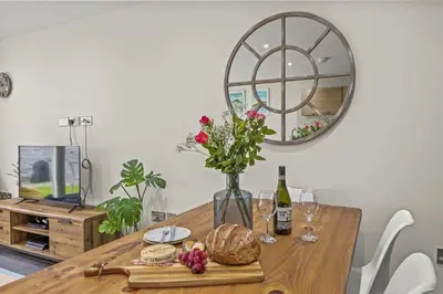 a table with a vase of flowers and a mirror at House 9 in Looe