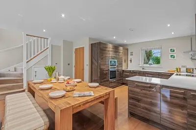 a large kitchen with a wooden table and a counter at House 7 in Looe
