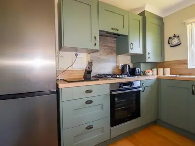 a kitchen with green cabinets and a stainless steel refrigerator at Lodge 9 - Lamorna in Padstow