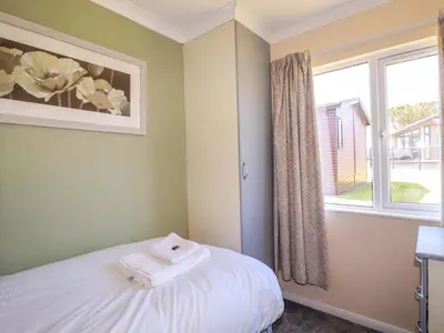 a bedroom with a bed and a window with towels at Lodge 9 - Lamorna in Padstow