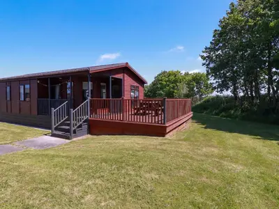 a house with a large deck on a grass field at Lodge 9 - Lamorna in Padstow