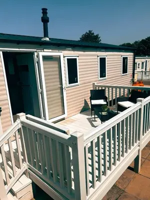 a mobile home with a deck with two chairs at Sandy Nights in Tywardreath