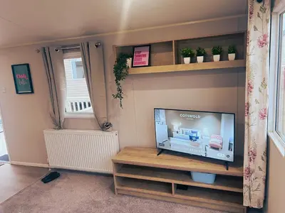 a living room with a flat screen tv on a shelf at Sandy Nights in Tywardreath
