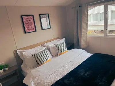 a bedroom with a bed with pillows and a window at Sandy Nights in Tywardreath