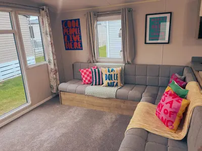 a living room with a couch and two windows at Sandy Nights in Tywardreath
