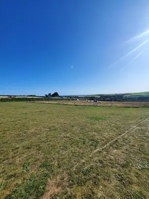 an empty grass field with the sky in the background at Monroe Horsebox Glamping in Porthleven