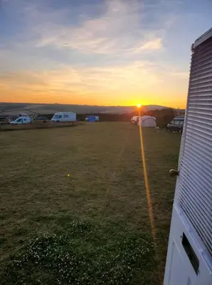 a view of a field with tents and the sunset at Monroe Horsebox Glamping in Porthleven