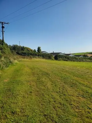 a field of grass with a power line in it at Monroe Horsebox Glamping in Porthleven