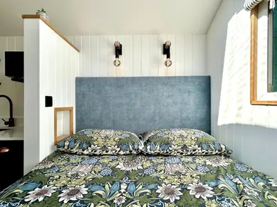 a bedroom with a bed with a blue head board at Luxury Shepherds Hut With Wood Fired Hot Tub in Mawgan Porth
