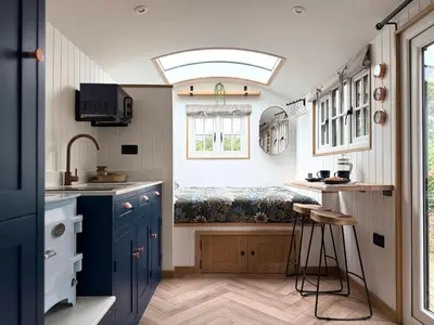 a small kitchen with blue cabinets and a window at Luxury Shepherds Hut With Wood Fired Hot Tub in Mawgan Porth