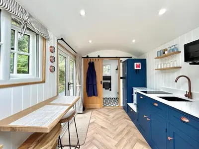 a kitchen with blue cabinets and a sink at Luxury Shepherds Hut With Wood Fired Hot Tub in Mawgan Porth