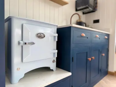 a kitchen with blue cabinets and a sink at Luxury Shepherds Hut With Wood Fired Hot Tub in Mawgan Porth