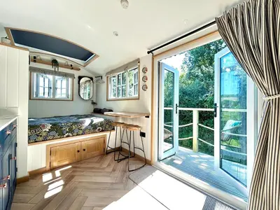 a small room with a bed and a large window at Luxury Shepherds Hut With Wood Fired Hot Tub in Mawgan Porth