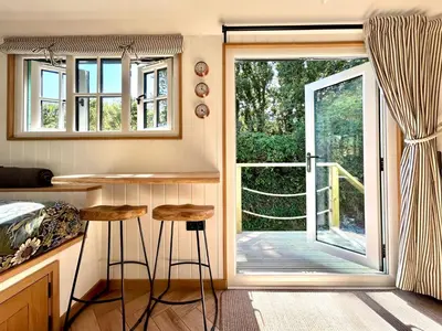 a tiny house with a kitchen and a sliding glass door at Luxury Shepherds Hut With Wood Fired Hot Tub in Mawgan Porth