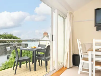 a room with a balcony with a table and chairs at 9 Slipway Cottages in Wadebridge